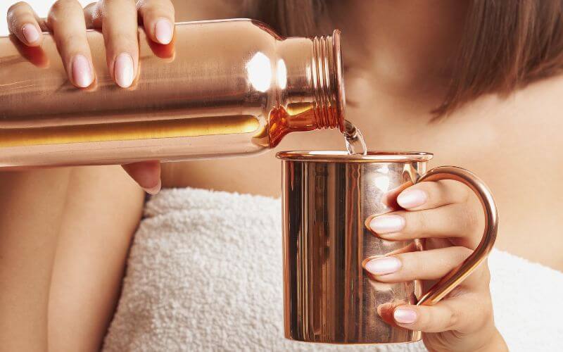 Woman holding a copper mug and bottle