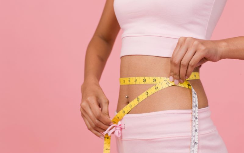 Woman measuring her waist with a tape measure