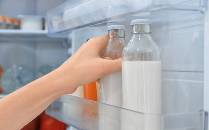 Woman putting a bottle in the refrigerator