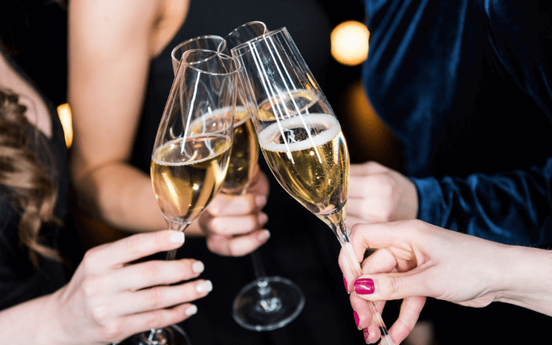 Women's hands clinking their glasses of Champagne