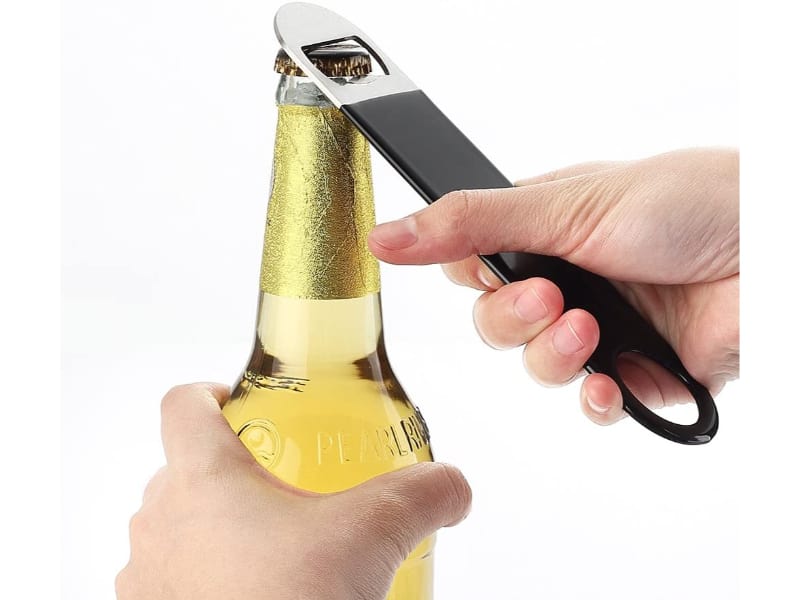 A bar key being used to open a bottle of beer