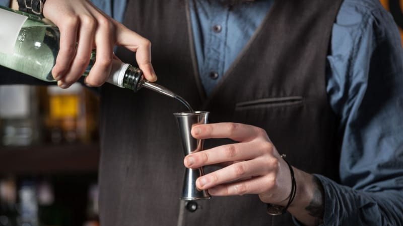 A bartender pouring liquor into a Japanese jigger