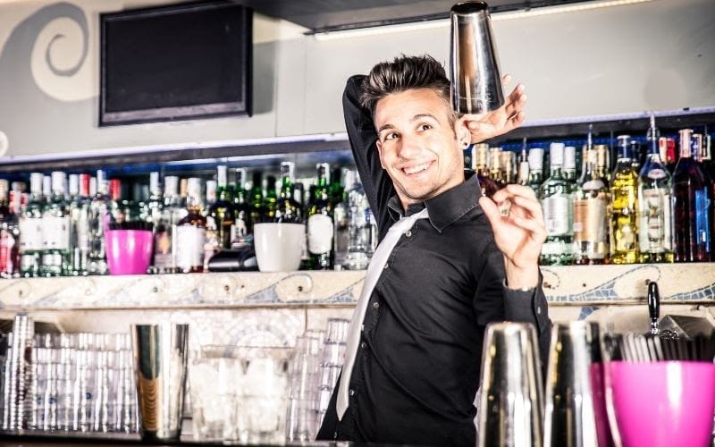 A bartender throwing cocktail shakers