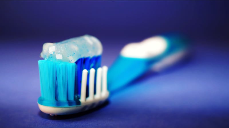 A blue toothbrush with toothpaste on it