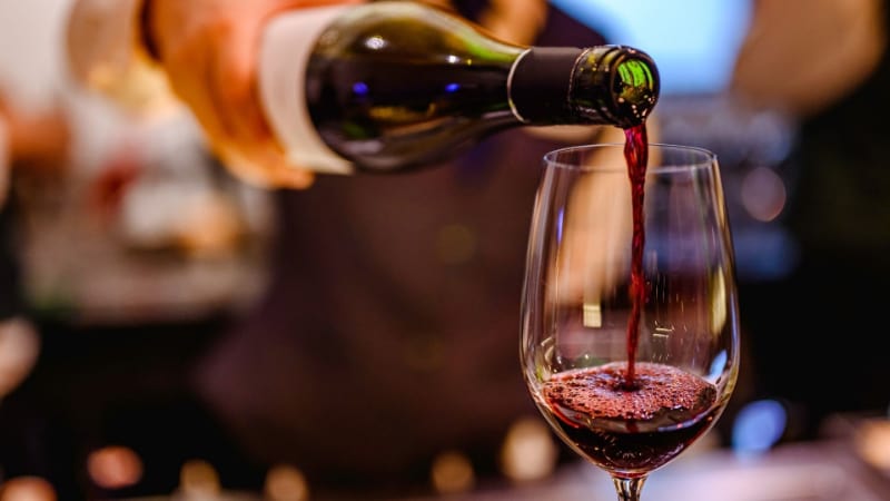 A bottle of wine being poured to a wine glass