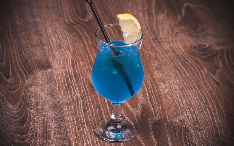 a glass and three shots of Deep Blue Sea Martini