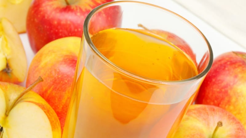 A glass of apple-ginger surrounded by apples