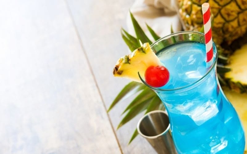 A glass of blue Hawaiian with a pineapple wedge