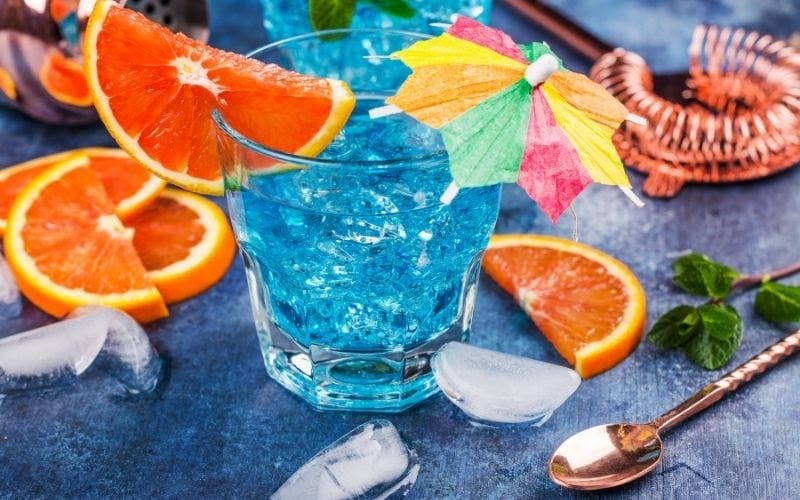 a glass of Blue Lagoon with orange wedges