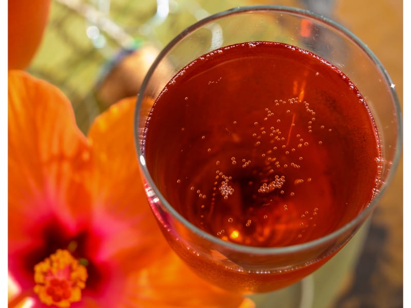 A glass of red drink with hibiscus flower served outside