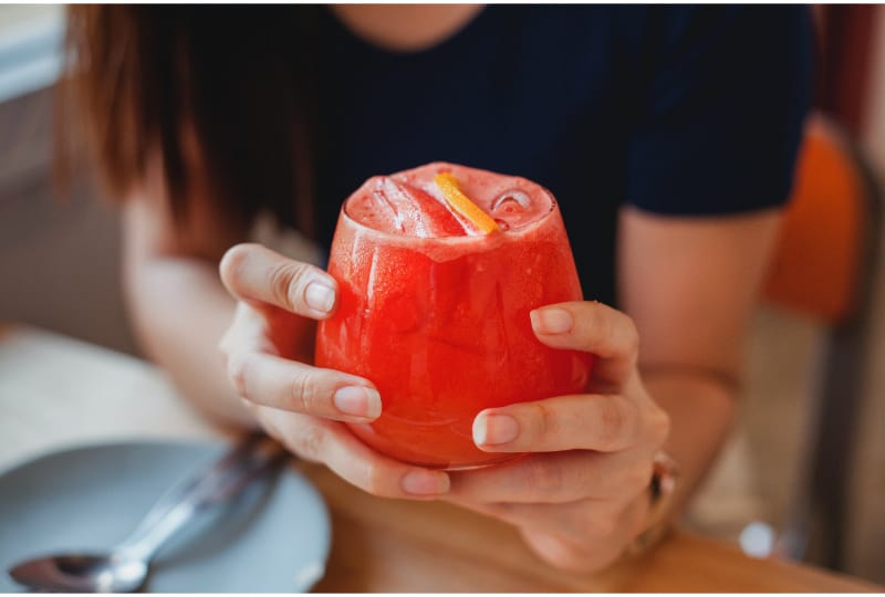 A person holding a red cocktail with both hands
