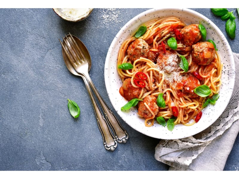  A serving of spaghetti and meatballs with utensils