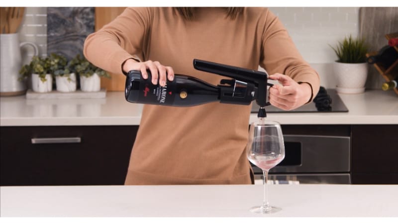 A woman pouring a wine using Coravin wine Aerator