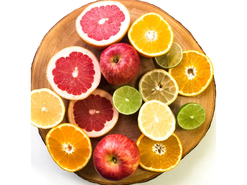 A wooden tray full of sliced citrus fruit and apples