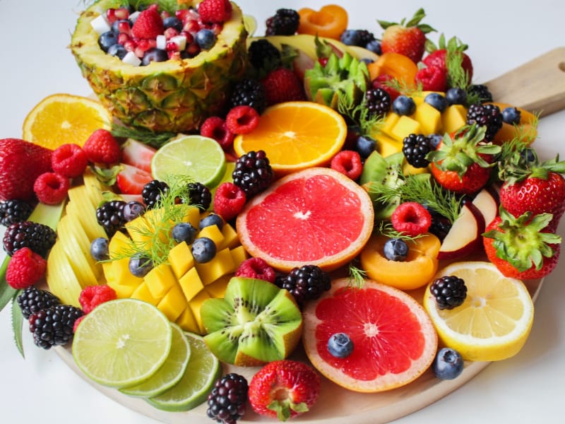 An assortment of sliced fruit on a wooden tray