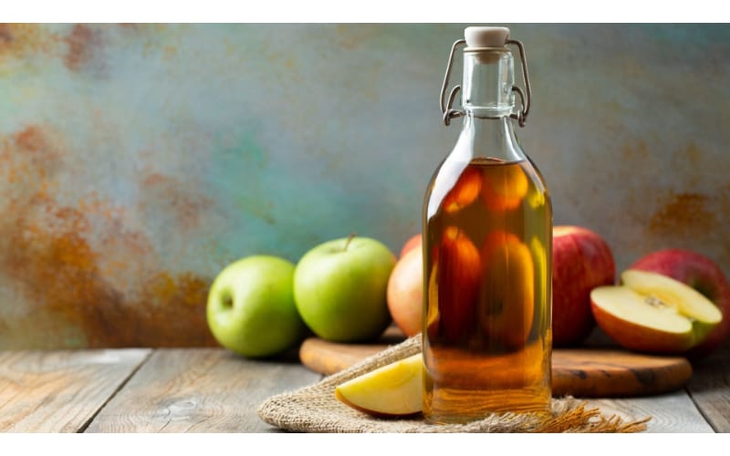 Apple cider vinegar bottle with fresh apples on the side