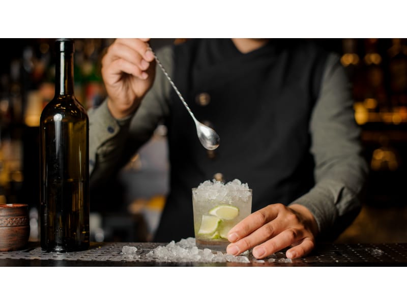 The hands of a professional bartender pour syrup into a measuring