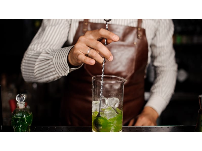 Bartender mixing cocktail using a bar spoon