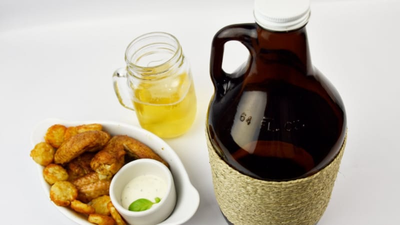 Black growler with a glass of beer and a dish finger foods
