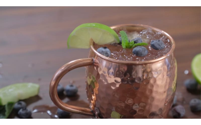 Blueberry Moscow Mule served on a copper mug and garnished with lime and blueberries