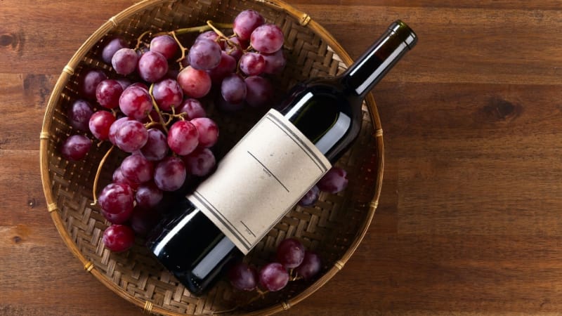 Bottle of red wine with grapes on a basket