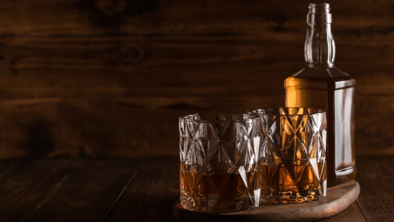 Bourbon in glass, american corn whiskey wooden background