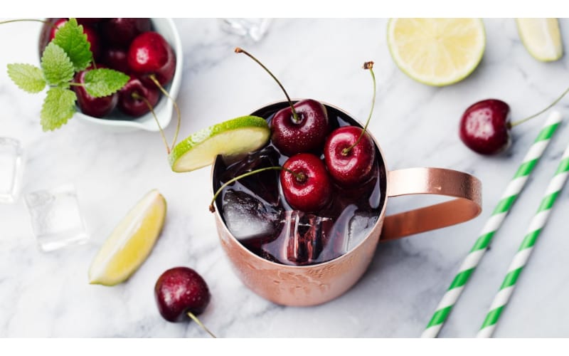 Cherry Moscow Mule served on a copper mug and garnished with lime and cherries