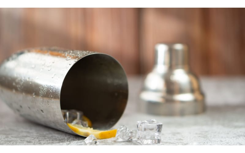 Cocktail shaker with ice cubes falling out the container