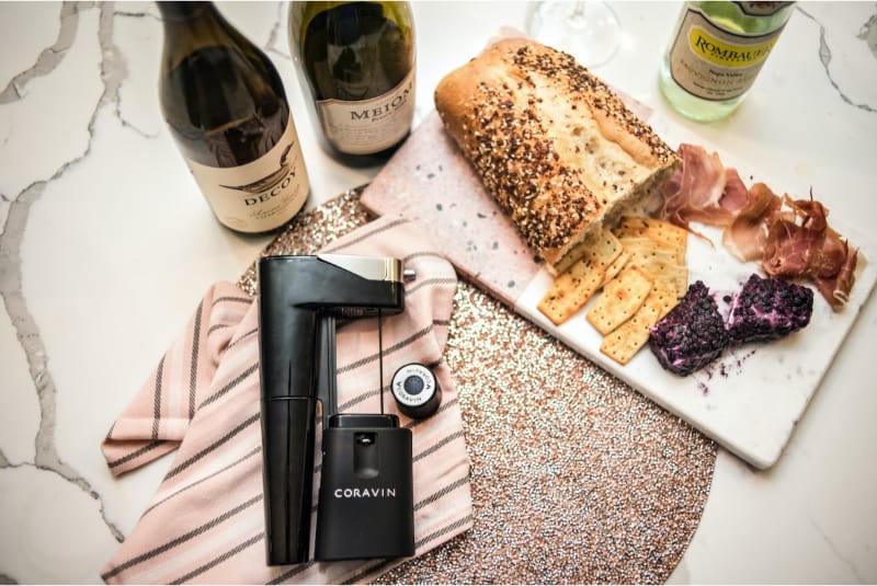 Coravin wine preservation system on a marble counter with bottles and charcuterie board