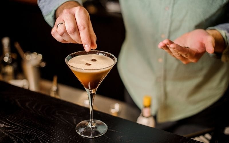 Bartender adding coffee beans to Espresso Martini 