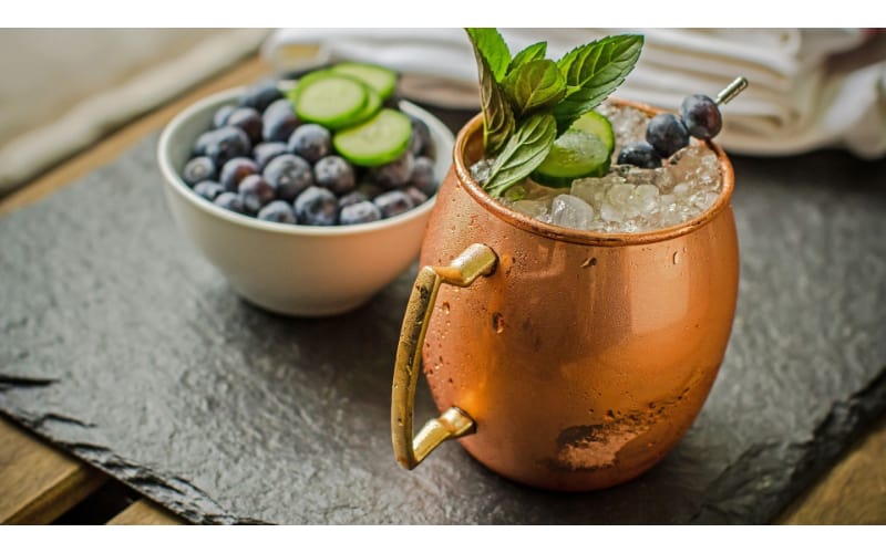 Garden Mule on a copper mug with a bowl of blueberries