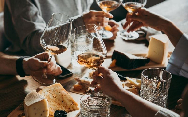 hands toasting glasses at a table