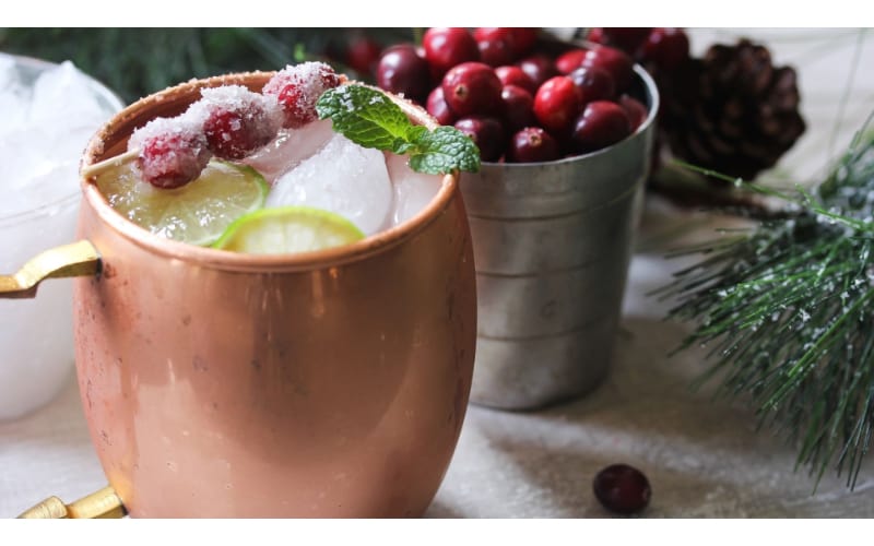 Holiday Mule served in a copper mug garnished with frozen cranberries