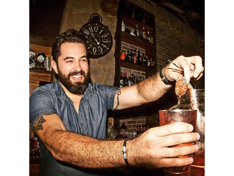 Israel Diaz pouring cocktail in a glass