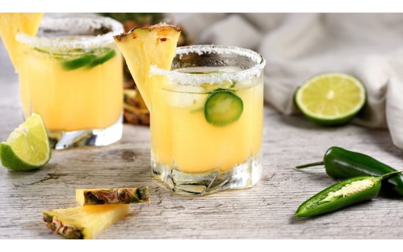 Jalapeno Moscow mule served in two glasses garnished with pineapple and lime