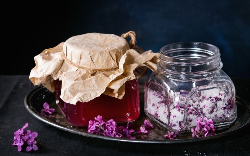 Jar of lilac cordial and another jar of lilac flowers and sugar