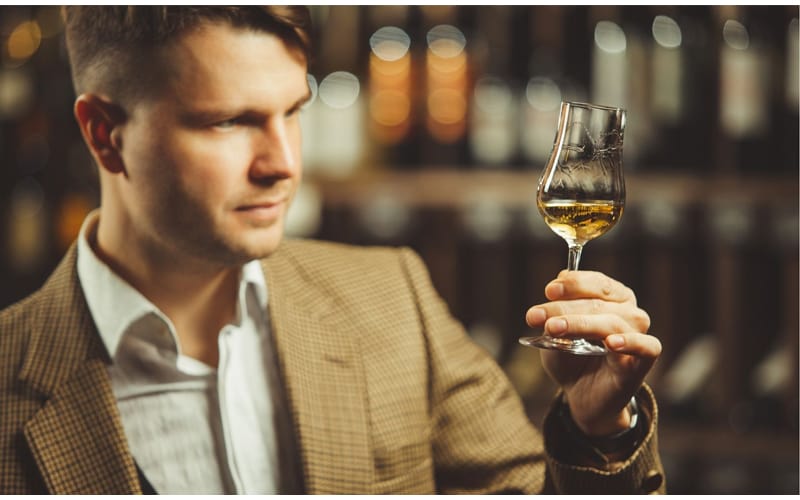 Portrait of male sommelier tasting whiskey at cellar