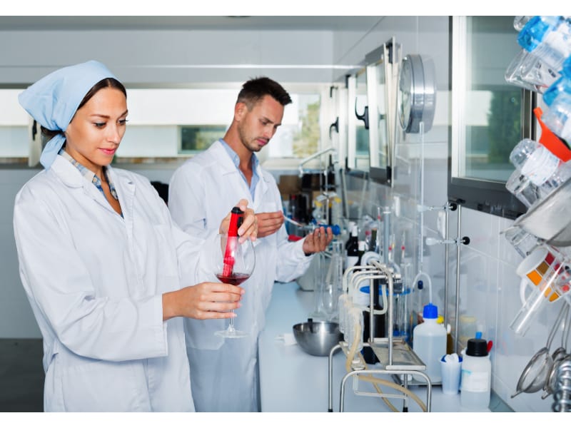 Chemists in a laboratory testing red wine