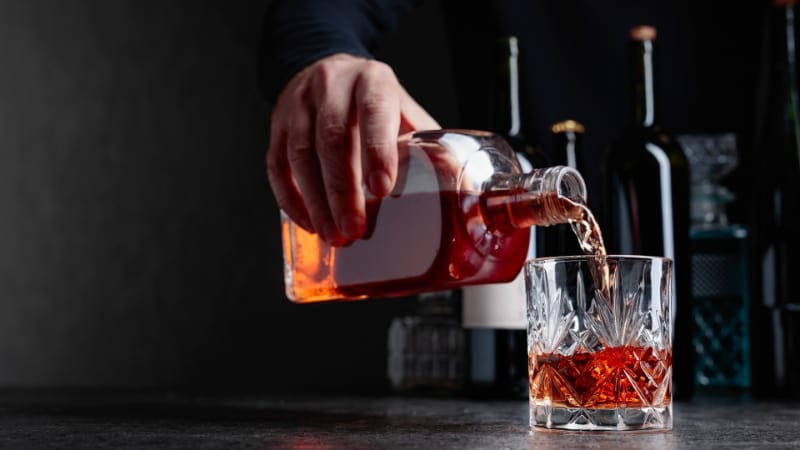 Man pours whiskey in a glass at the bar