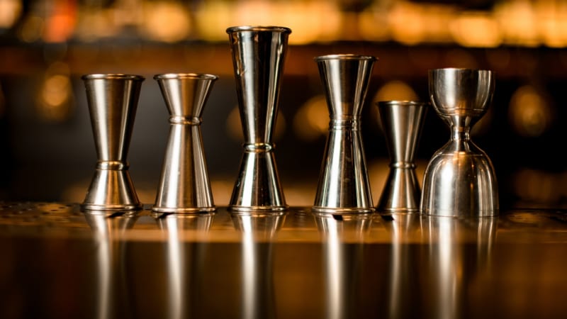 Many different jiggers stands in row on the bar counter