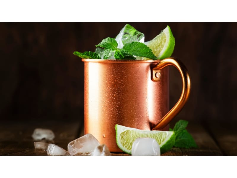 Mint julep in a copper mug with ice cubes and lime on the side