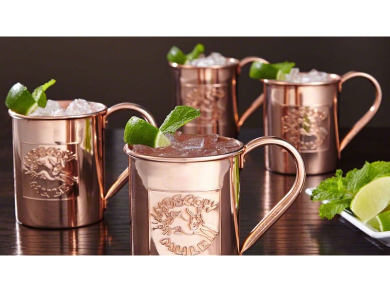 Four servings of Moscow mule with lime and mint in copper mugs