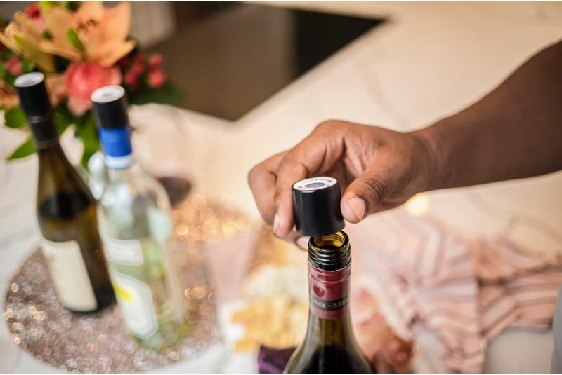 Man holding a Coravin screw cap on top of a wine bottle