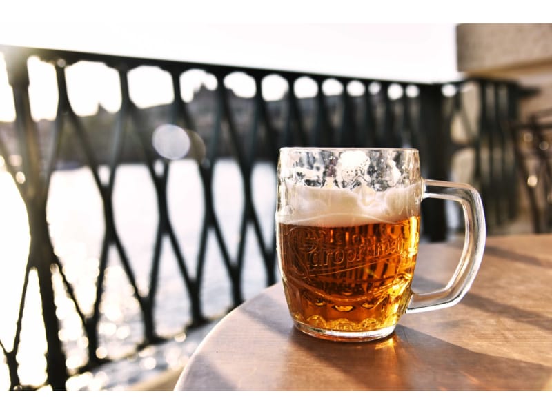 Mug of beer on top of a table in front if the sea