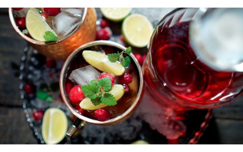 Pomegranate Mule served in mason jars with lemon and pomegranate seeds as garnish