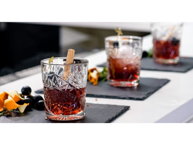 A tastefully designed rocks glass with premium whiskey and ice, served with fruits on the side. 