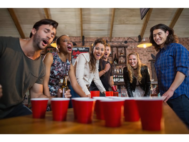 Young friends playing beer pong game in bar