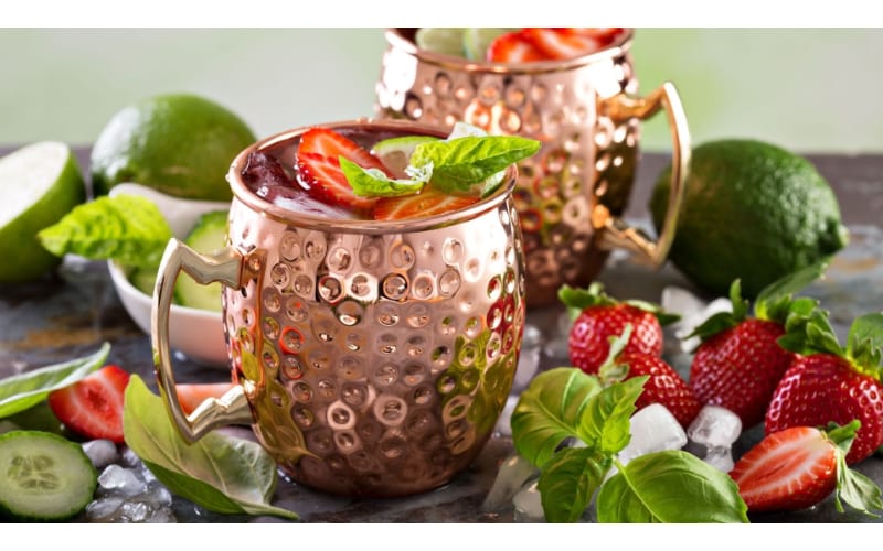 Strawberry Moscow mule served in two copper mugs garnished with strawberry slices and mint
