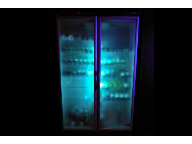 Glowing iced cold wine bottle fridge in darkness