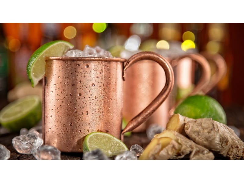 Whiskey ginger mule in a copper mug with ginger flesh on the side